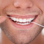Dental, floss and closeup of man with teeth whitening, fresh breathe and cavity prevention for health and hygiene. Oral care, string or thread for orthodontics with veneers and mouth cleaning
