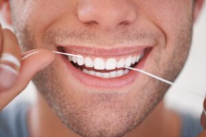 Dental, floss and closeup of man with teeth whitening, fresh breathe and cavity prevention for health and hygiene. Oral care, string or thread for orthodontics with veneers and mouth cleaning